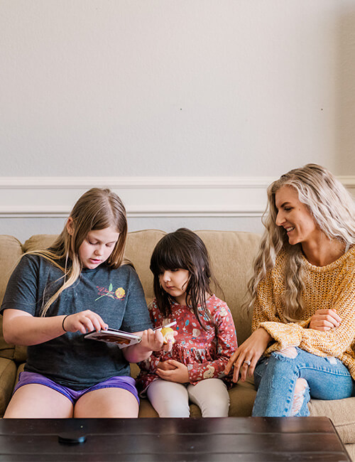 Preteen girl with little girl and Babysitter looking at a book
