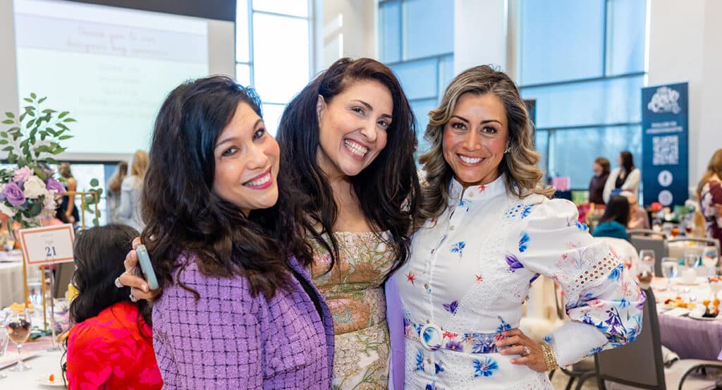 Three women dressed up and smiling at the Christ's Haven Fashion Show